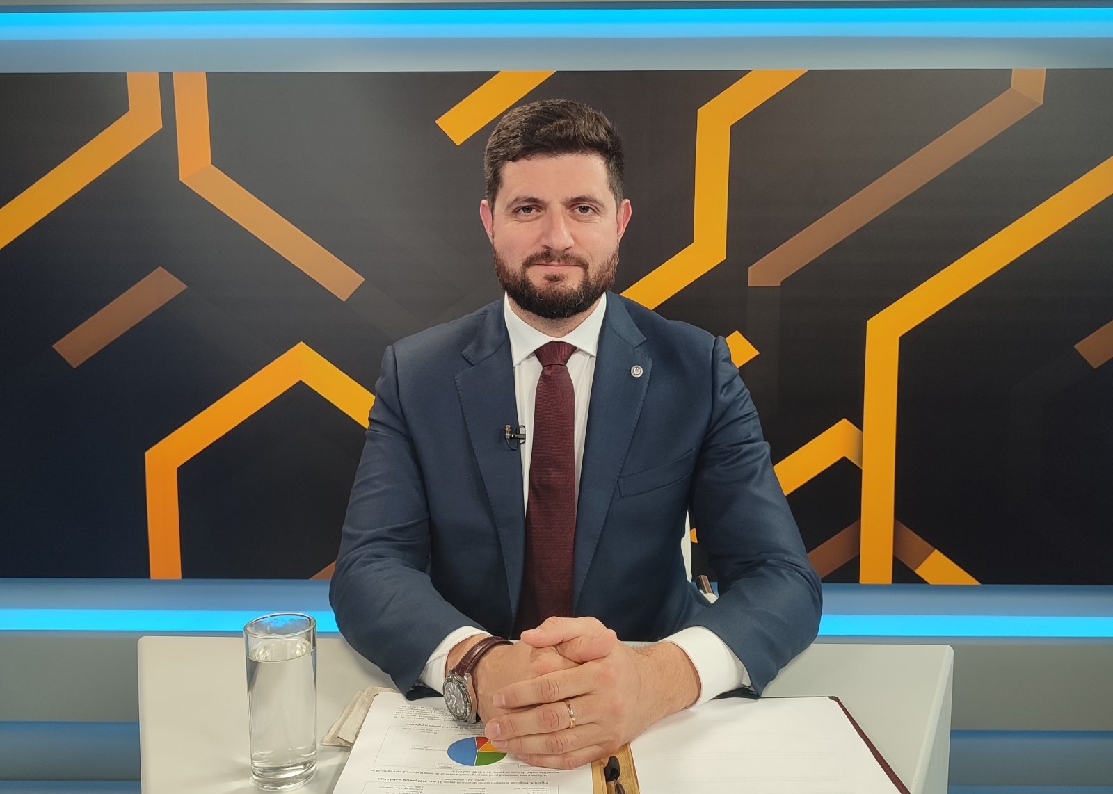 Министр энергетики Молдовы Дорин Жунгиету в телестудии за рабочим столом с документами