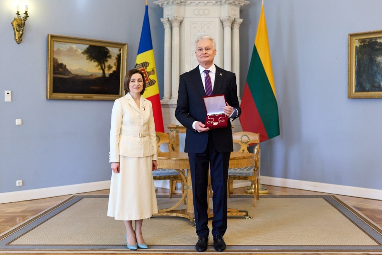 Майя Санду вручает Орден Республики президенту Литвы Гитанасу Науседе в парадном зале на фоне флагов обеих стран