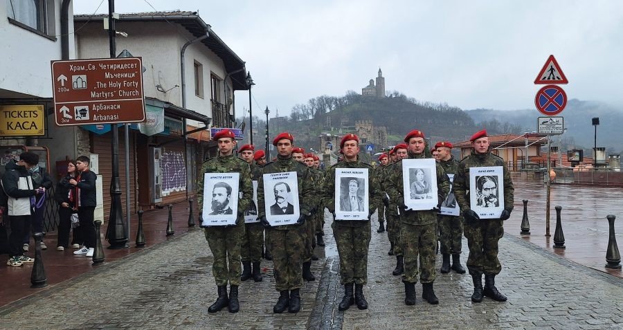 Военнослужащие в красных беретах несут портреты исторических деятелей по улицам старого города — на заднем плане видна крепость Царевец