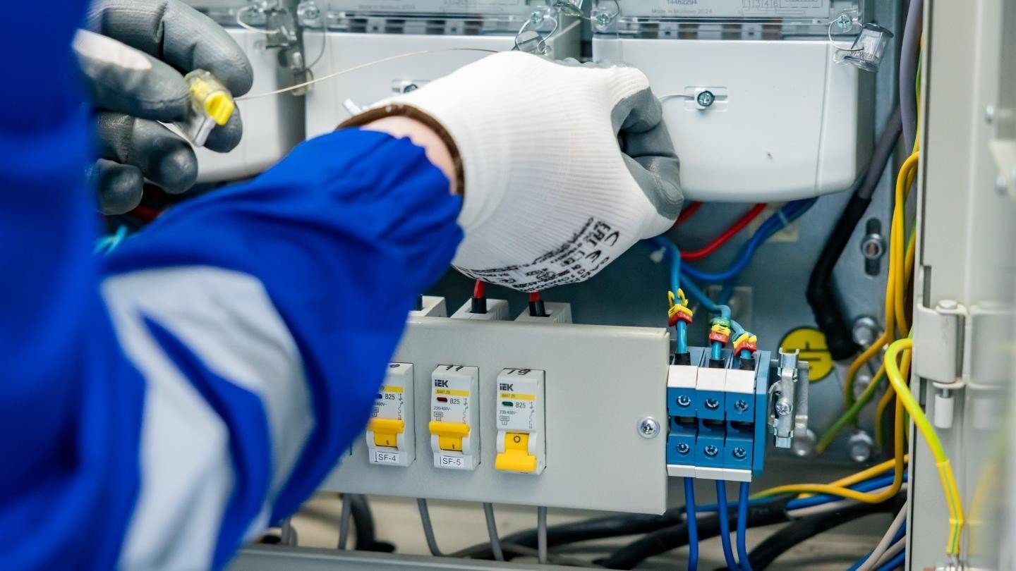 Электрик проводит работы на распределительном щите с автоматическими выключателями в ходе модернизации энергетической инфраструктуры