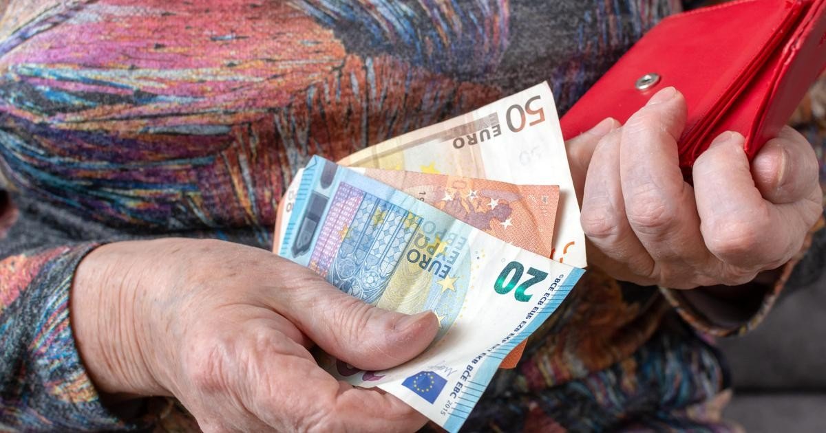 Руки пожилого человека с купюрами евро, извлечёнными из красного кошелька — расходы домохозяйств на электроэнергию