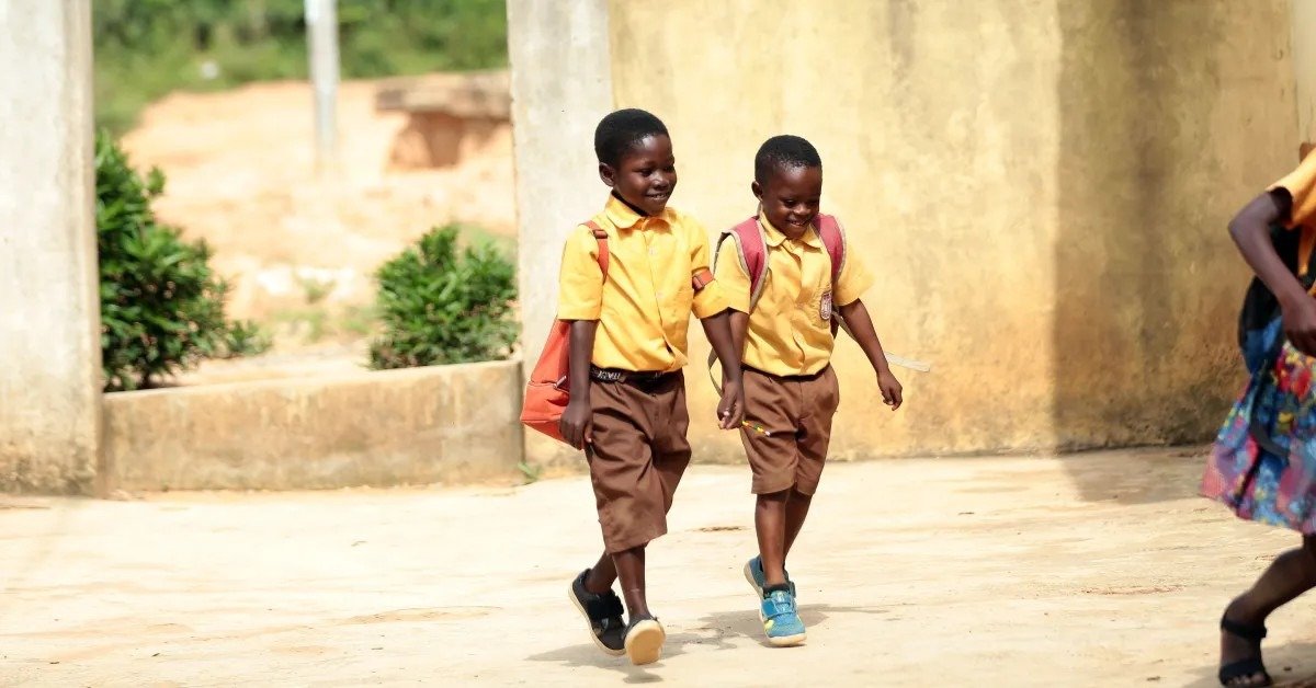 Двое школьников в форме идут с рюкзаками на занятия