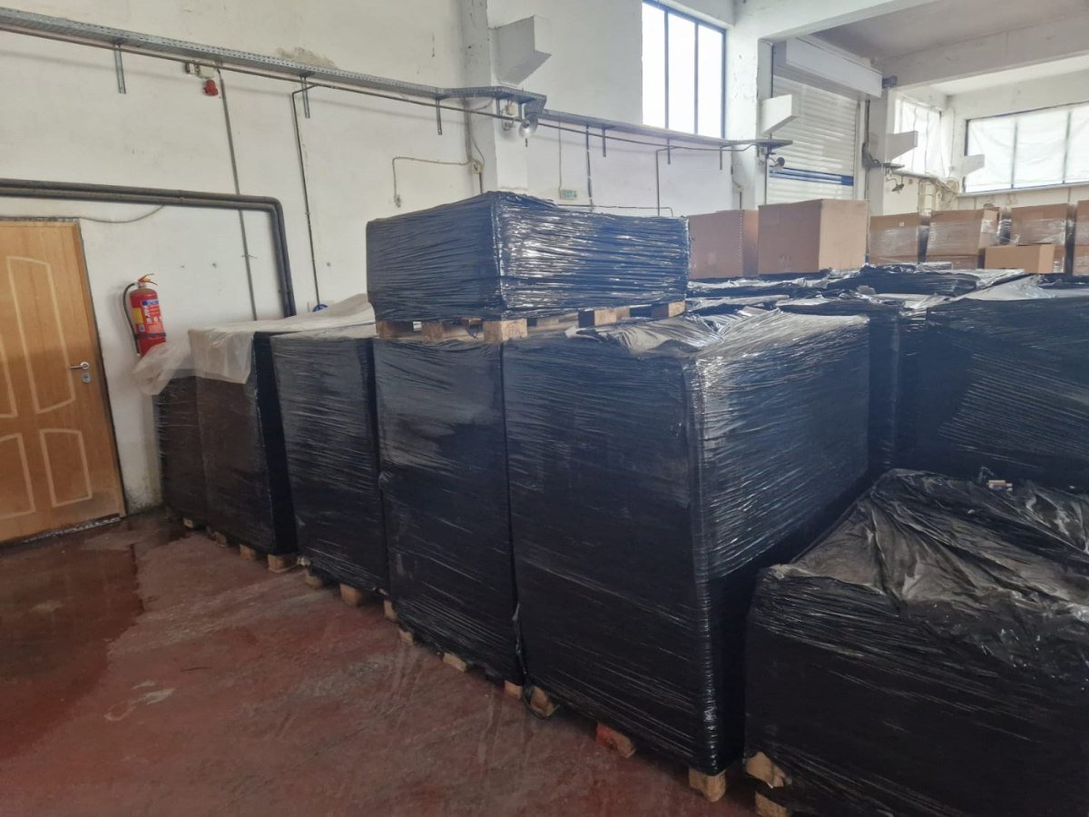 Склад с изъятым контрабандным товаром в черной пленке на поддонах. Фото: in.gr