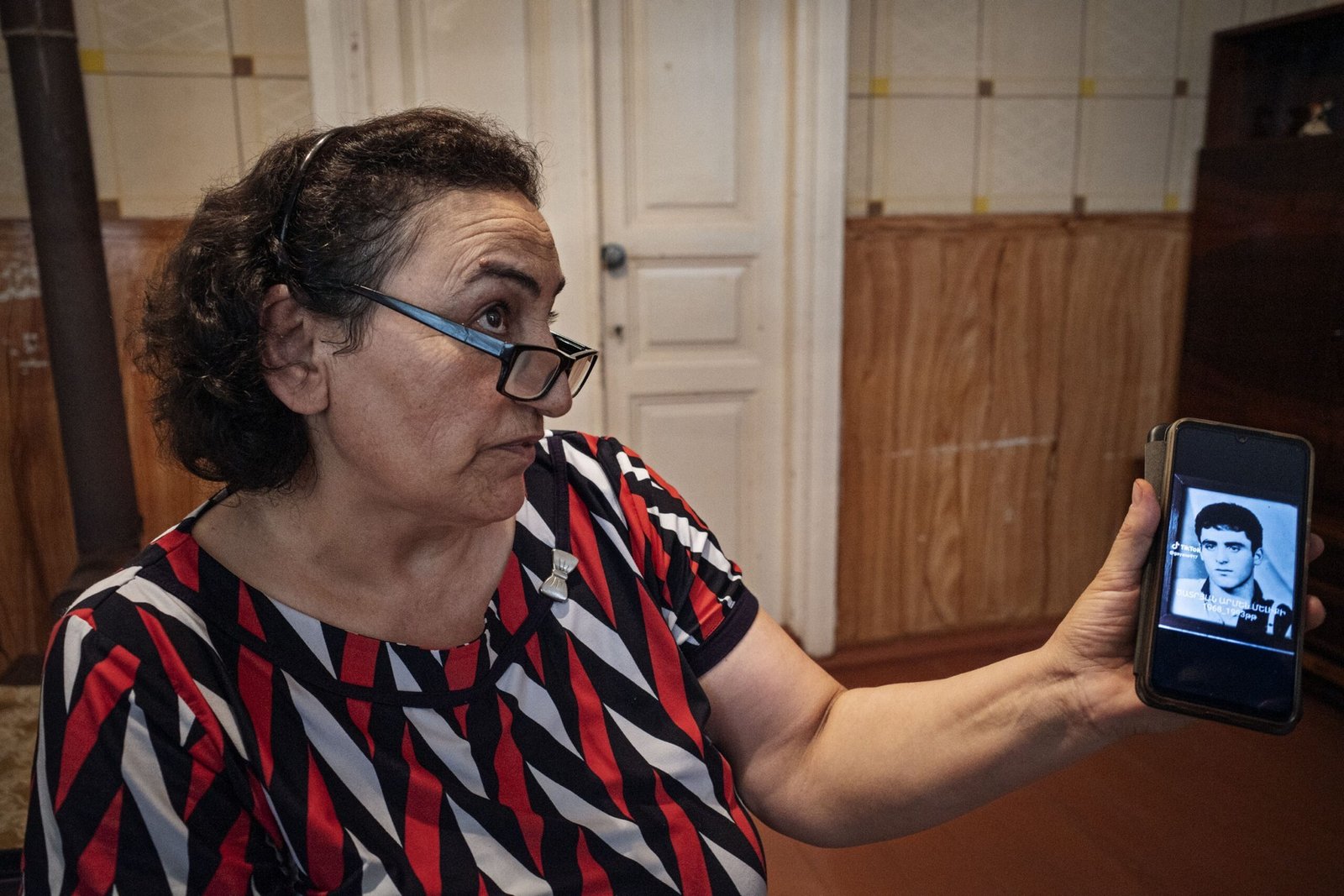 Жительница Сюникской области показывает на телефоне фотографию родственника