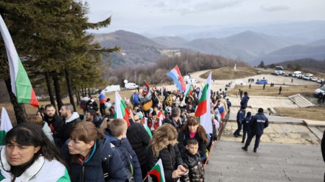 Люди с флагами Болгарии идут к памятнику на Шипке
