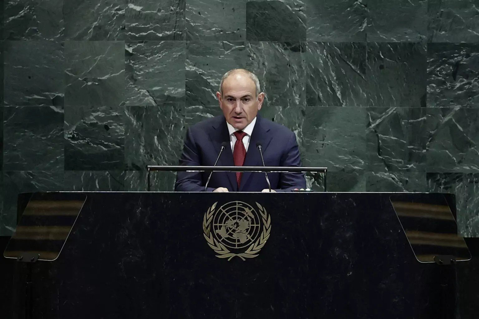 Официальное лицо выступает на трибуне ООН с эмблемой организации. Фото: Unknown