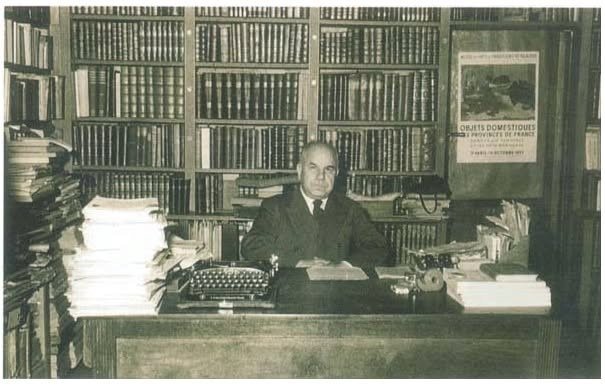 Историческая чёрно-белая фотография Гранта Самуэляна за рабочим столом в «Восточной книжной лавке» в окружении книжных полок