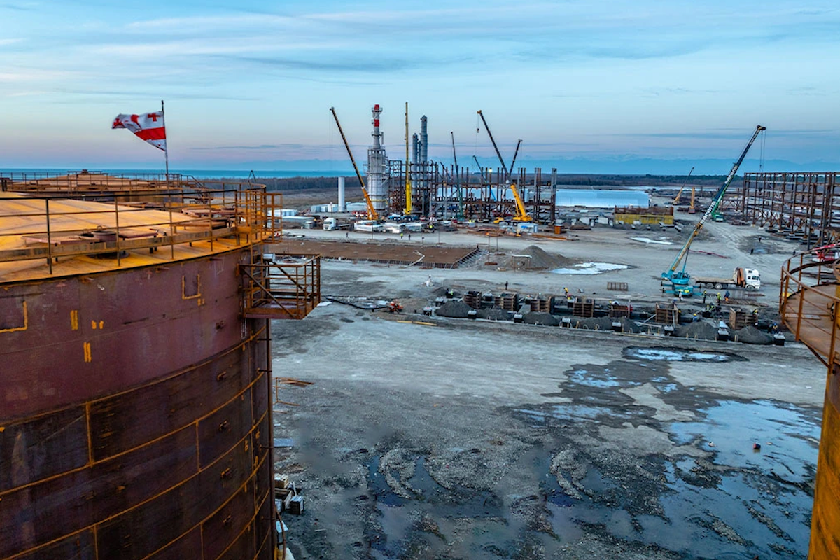Строительная площадка нефтеперерабатывающего объекта — краны, стальные конструкции и грузинский флаг на резервуаре