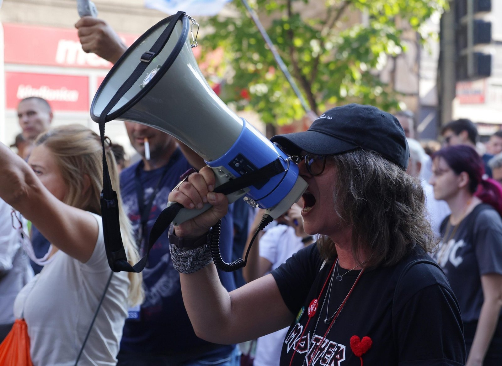 Женщина с мегафоном на уличном протесте в Сербии, окруженная толпой демонстрантов. Фото: EUAlive
