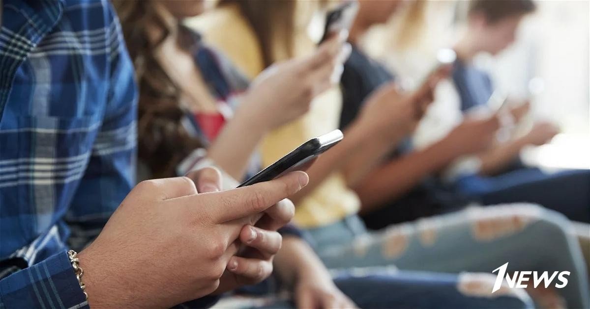 Подростки сидят в ряд, пользуясь смартфонами. Фото: 1news.az