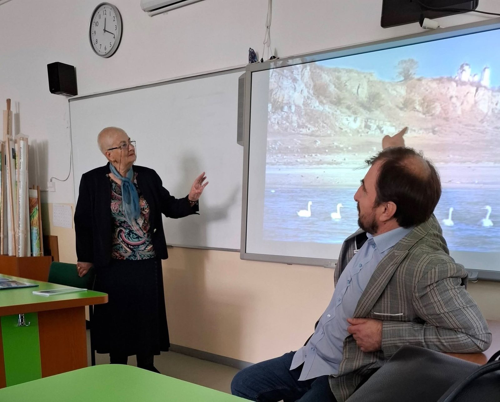 Участники мероприятия обсуждают тему охраны водных экосистем, на экране проектора — река с лебедями