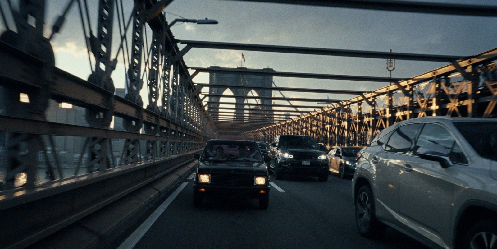 Yugo проезжает по Бруклинскому мосту на закате среди современных автомобилей — атмосферный кадр из документального фильма «Yugo Goes to America»