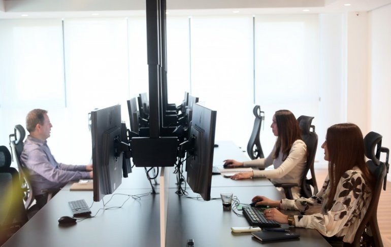 Сотрудники за рабочими станциями с мониторами в обновлённых помещениях Белградской биржи