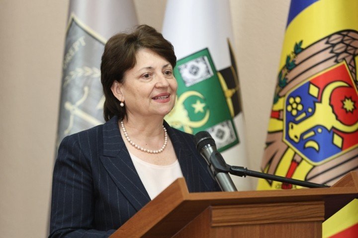 Выступление представителя Министерства образования на церемонии открытия олимпиады на фоне государственных флагов Молдовы