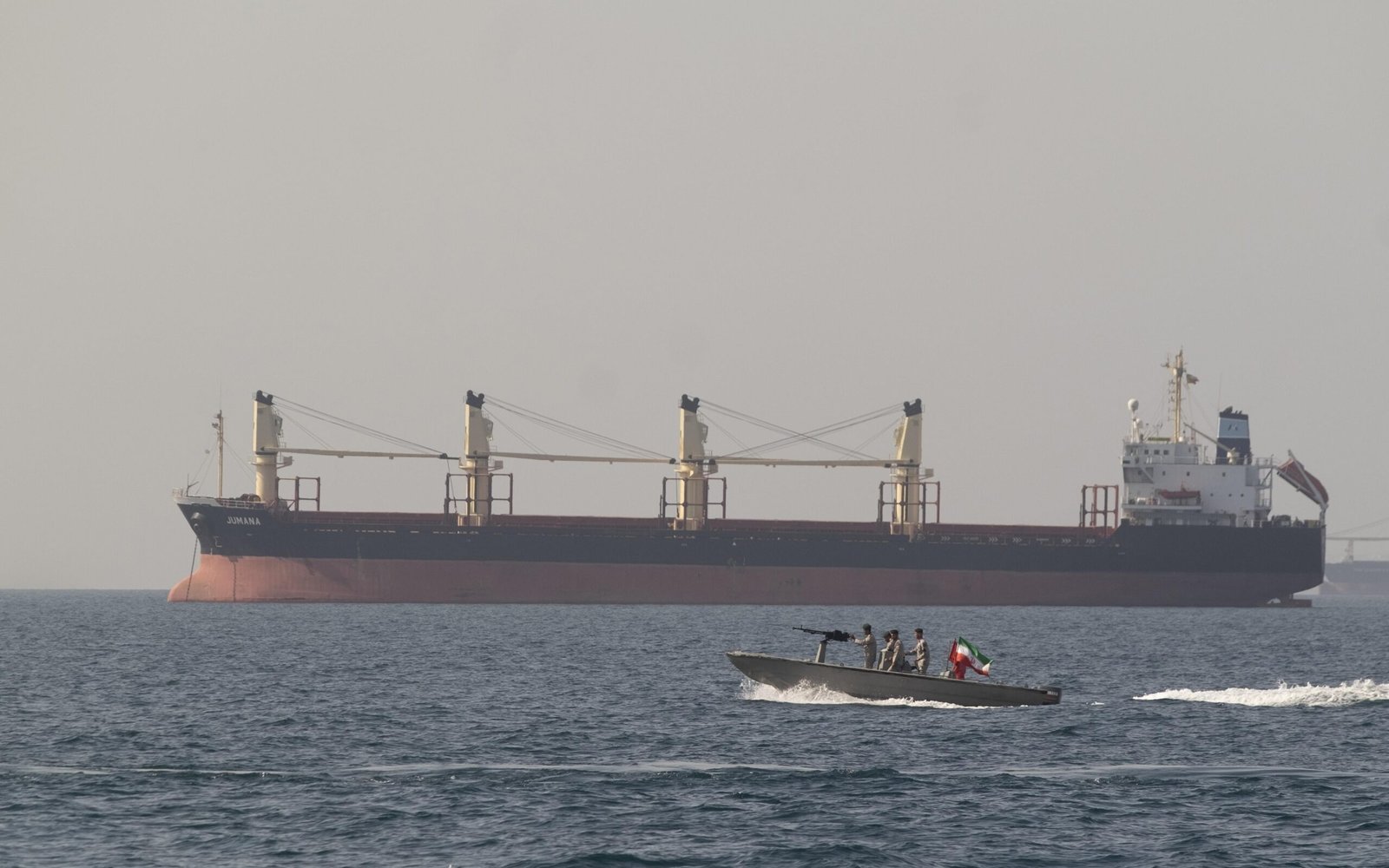 Cargo tanker ship with armed speedboat in foreground flying Iranian flag, illustrating Middle East maritime tensions