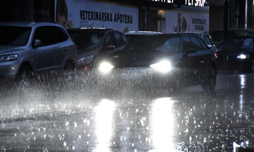 Холодная волна в Сербии: реки выходят из берегов Автомобили едут по затопленной дождём городской улице ночью, фары пробиваются сквозь стену ливня