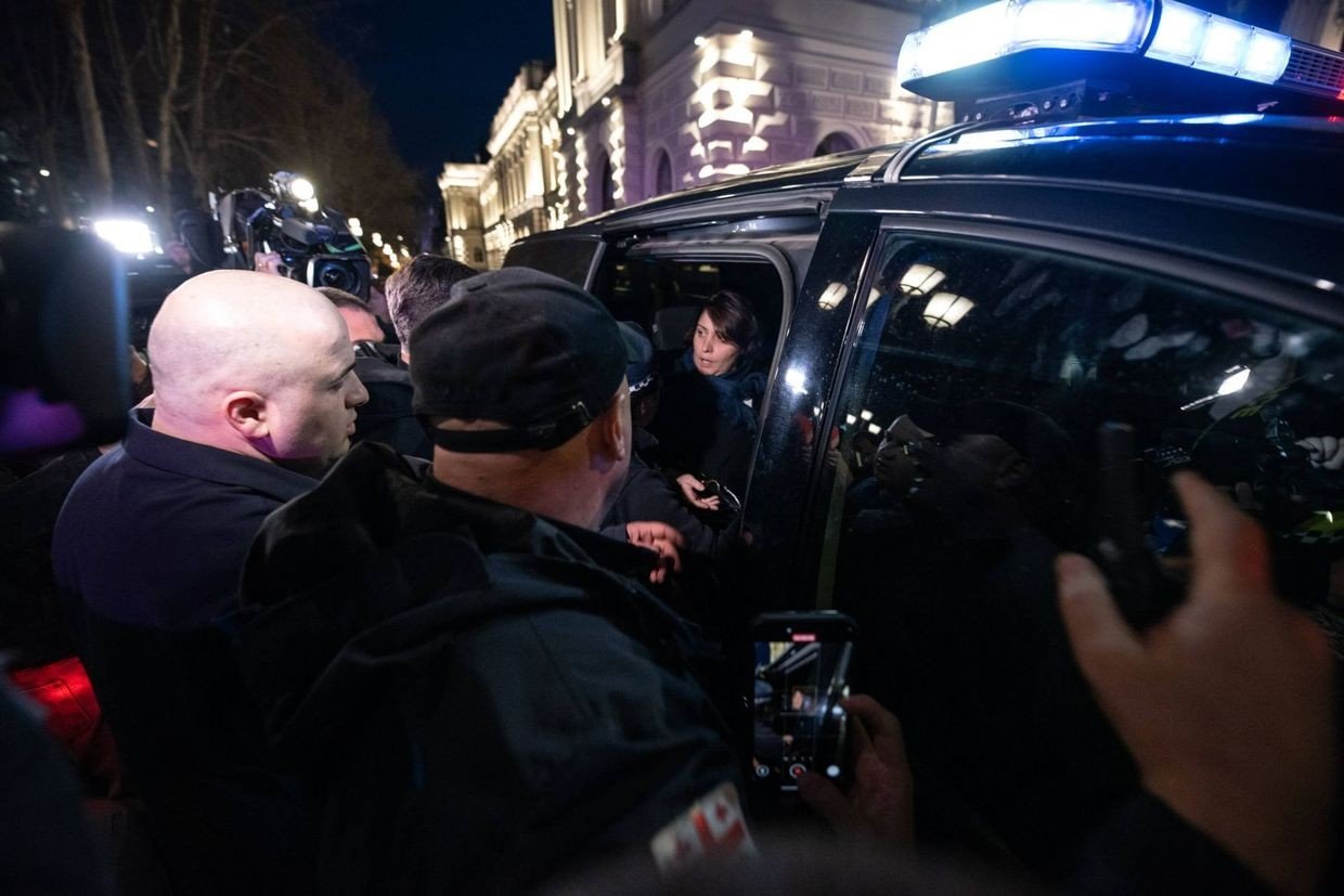 Opposition leader Elene Khoshtaria in police vehicle during detention, surrounded by press and security. Фото: OC Media