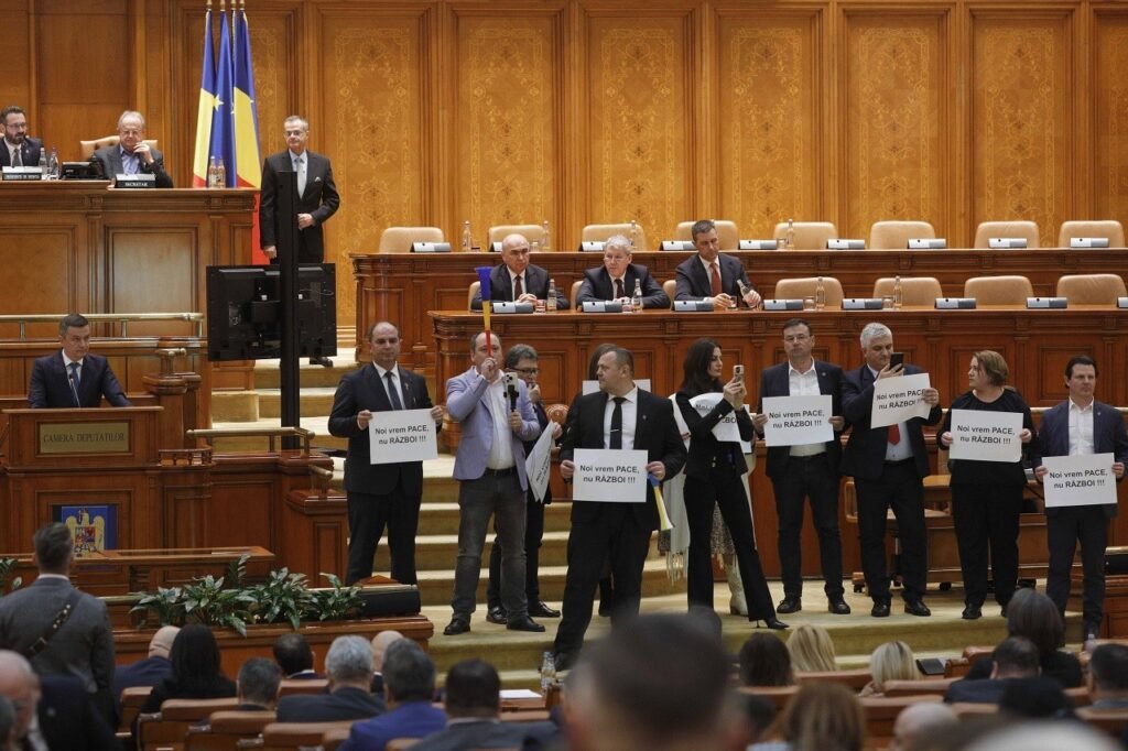 Депутаты румынского парламента протестуют с плакатами «Мы хотим мира, а не войны» во время голосования по размещению американских войск