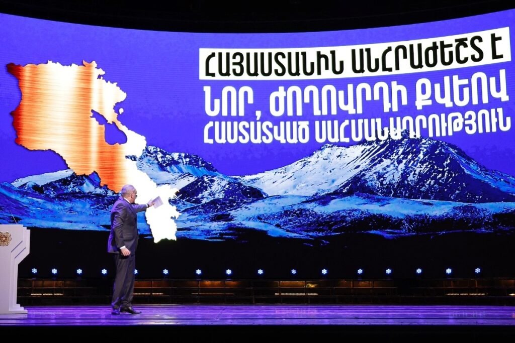 Армения переписывает конституцию: между миром и суверенитетом Премьер-министр Никол Пашинян на сцене представляет проект новой конституции Армении на фоне карты страны