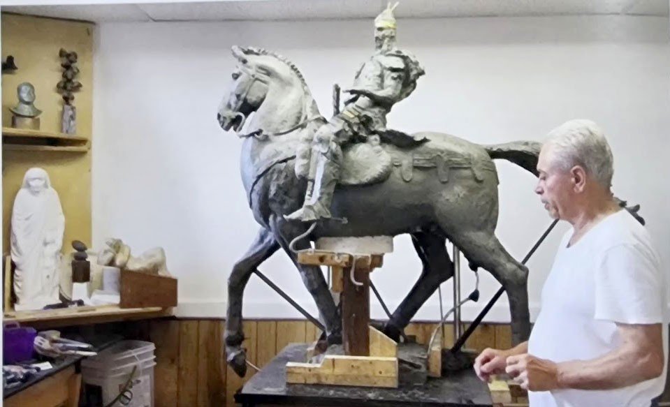Васил Ракай в мастерской рядом с монументальной конной статуей Скандербега, демонстрирующей масштаб его работ