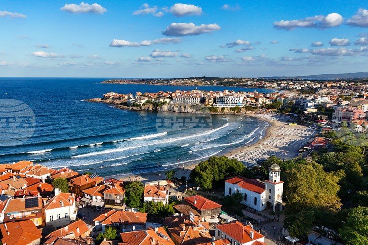 Панорама болгарского черноморского курорта с высоты — песчаный пляж, волны, черепичные крыши и набережная в солнечный день