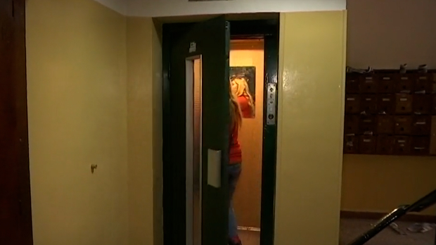 Женщина входит в старый лифт в подъезде жилого дома