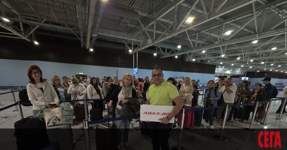 Большая группа болгарских туристов ожидает в терминале аэропорта с багажом, представитель туроператора ABAX.BG с табличкой. Фото: Sega
