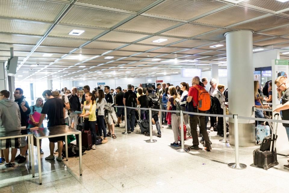 Large crowd of passengers queuing at airport passport control with luggage. Фото: ETIAS.com