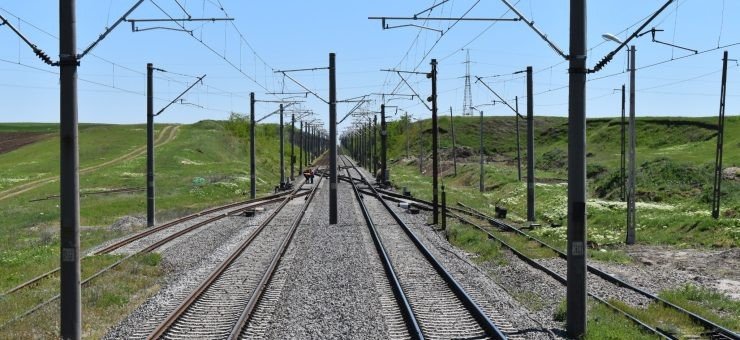 Новые электрифицированные железнодорожные пути, уходящие вдаль, с опорами контактной сети по обеим сторонам