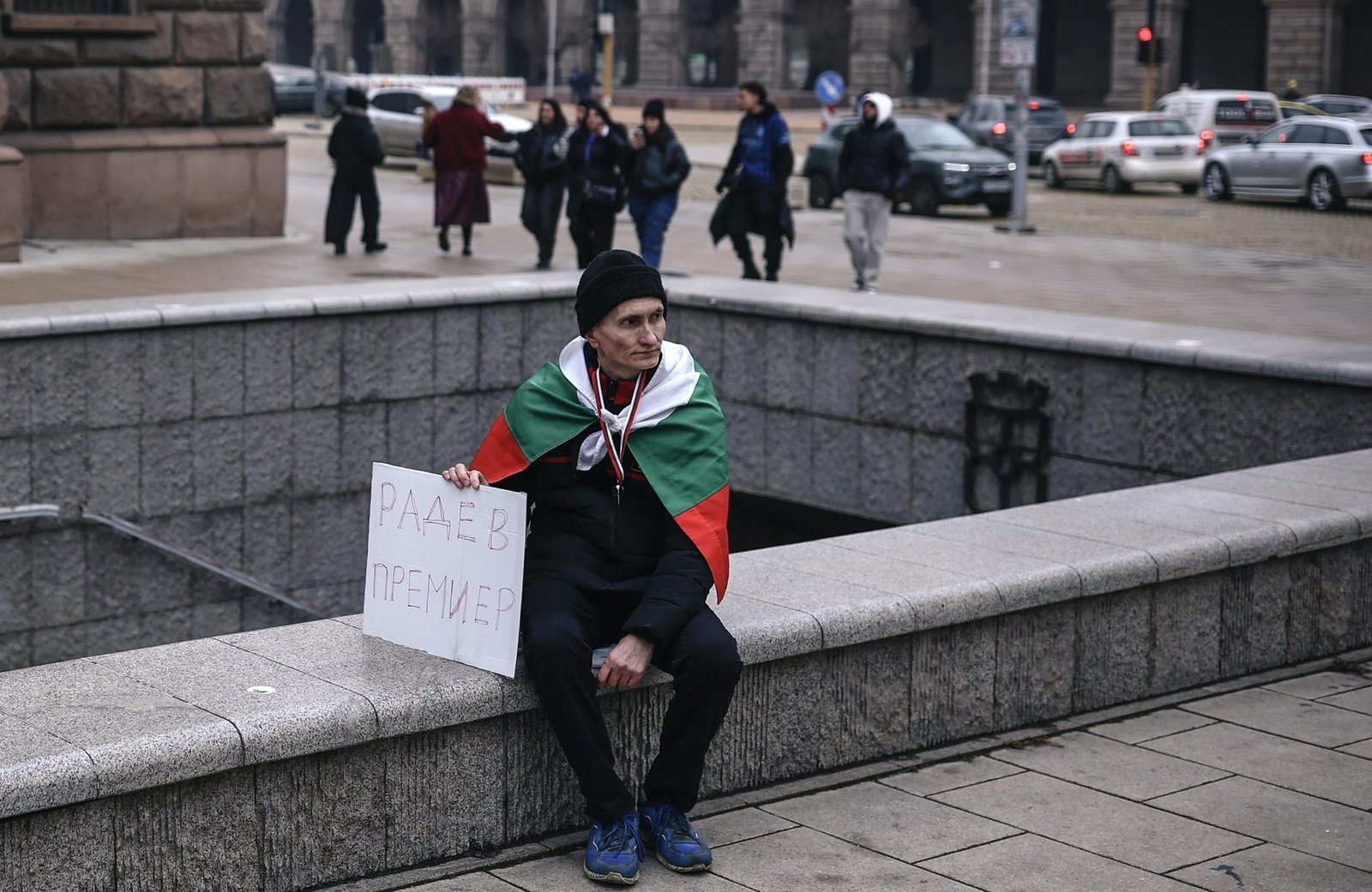 Сторонник Радева, завернувшийся в болгарский флаг, держит плакат «Радев в Премиер» в центре Софии
