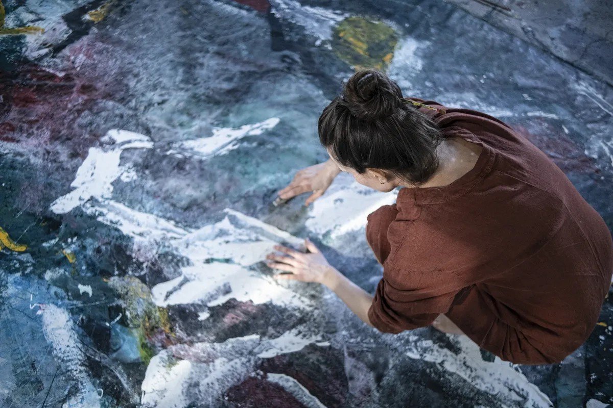 Наталия Миладинович за работой над большим холстом — художница наносит краску вручную в своей авторской технике