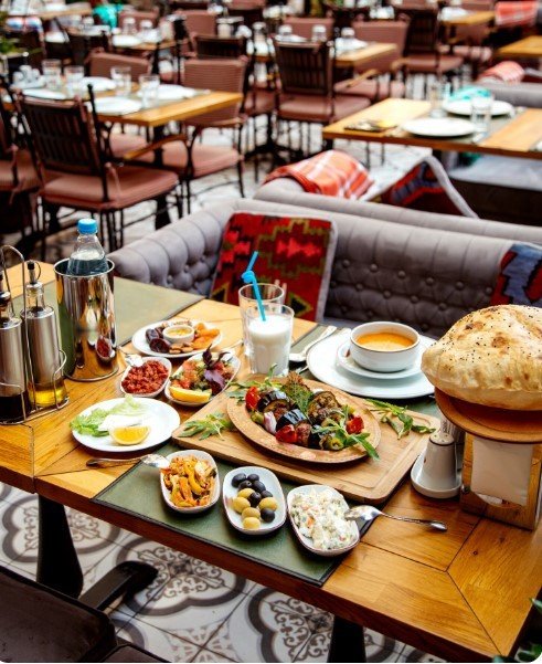 Богато сервированный стол в ресторане с разнообразными блюдами балканской кухни, кофе и свежим хлебом