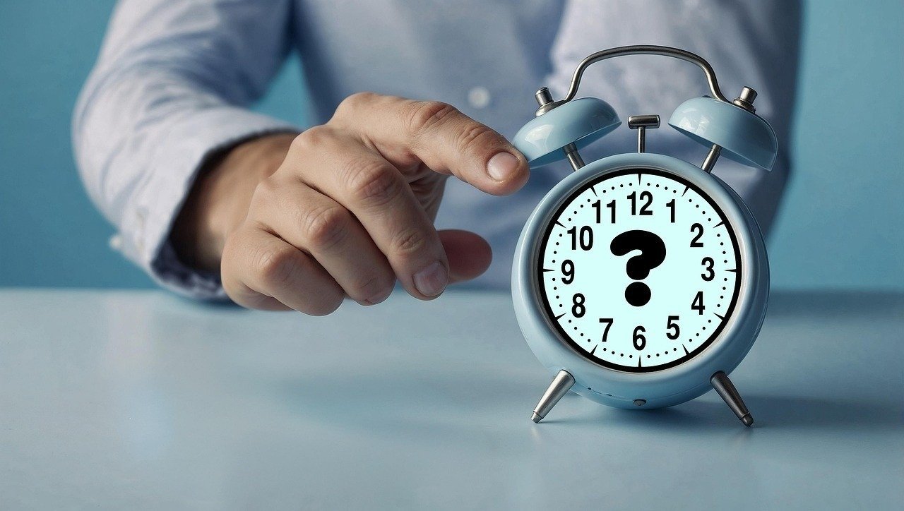 Голубой будильник с вопросительным знаком на циферблате — символ неопределённости при переводе часов