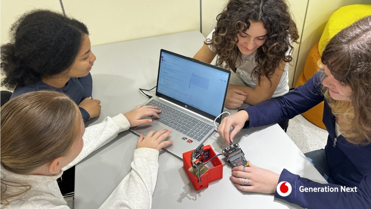 Четыре ученицы команды CALMify AI работают над проектом управления учебным стрессом с помощью ноутбука и электронного устройства