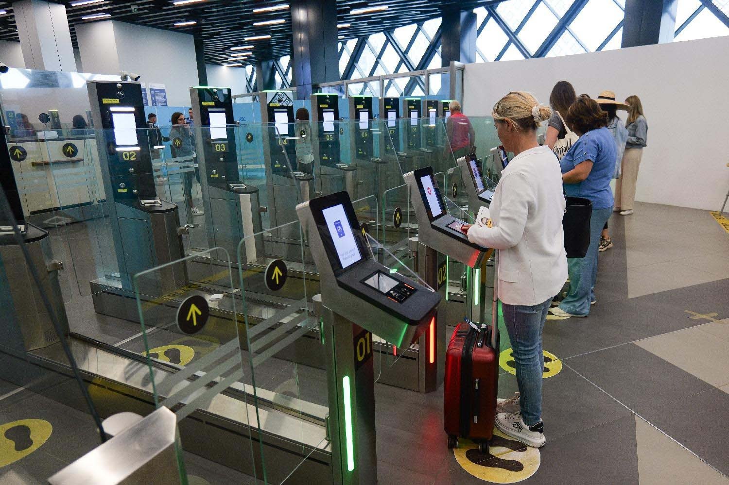 Passengers using automated e-gates with biometric screens at airport border control. Фото: Danas