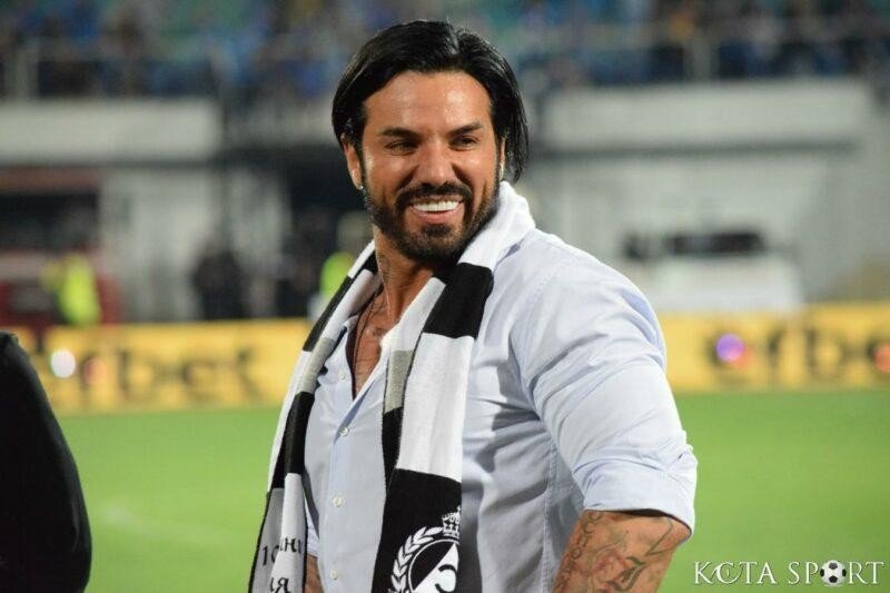 Болгарский футболист Благо Георгиев улыбается на стадионе в черно-белом шарфе. Фото: KotaSport