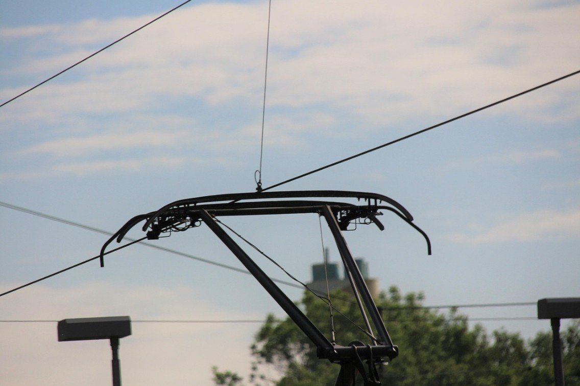 Токосъёмник (пантограф) электровоза на фоне контактных проводов и облачного неба