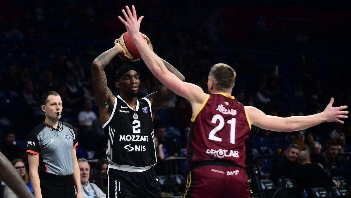 Баскетболист «Партизана» с мячом в руках в противостоянии с защитником «Босны» под контролем арбитра