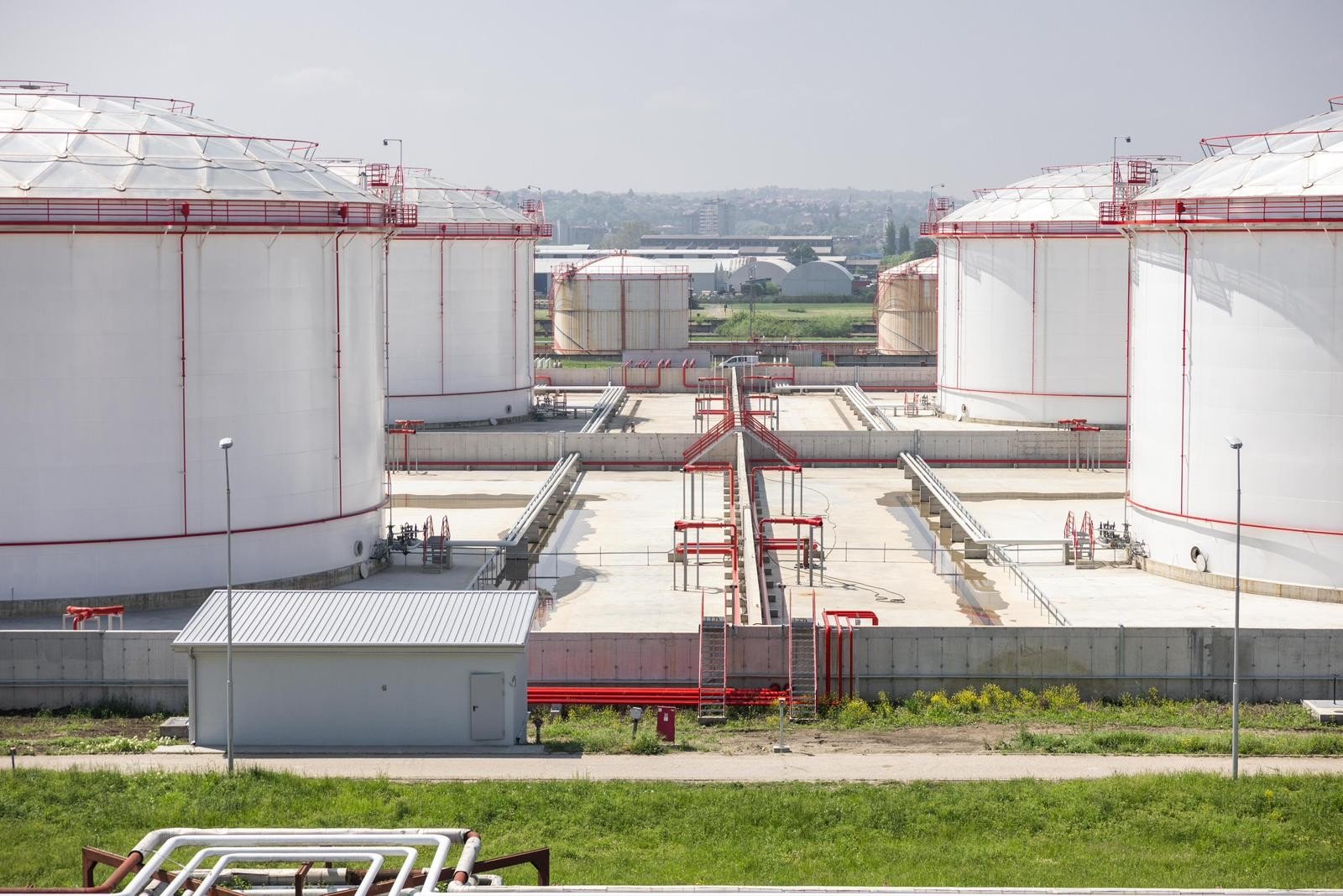 Large white petroleum storage tanks at industrial facility with red pipelines. Фото: ceenergynews.com