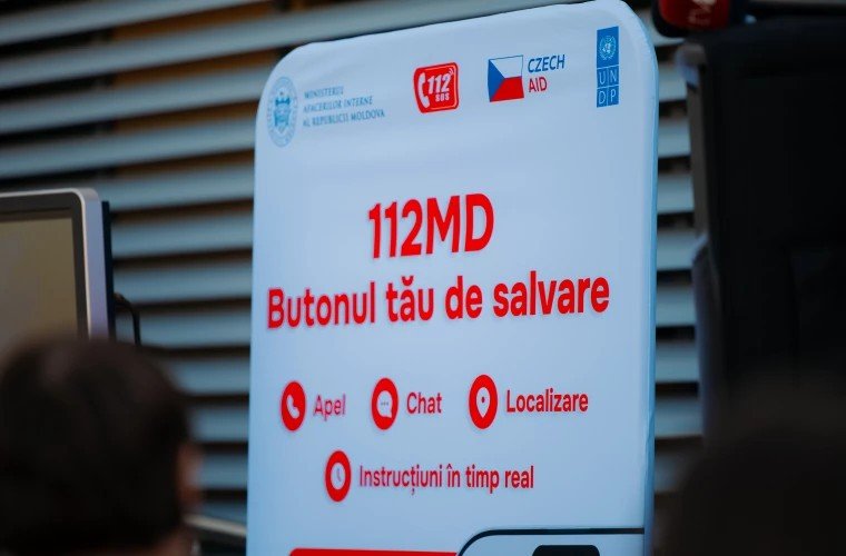 Презентационный стенд приложения 112MD на церемонии запуска с перечнем функций: звонок, чат, локализация и инструкции в реальном времени