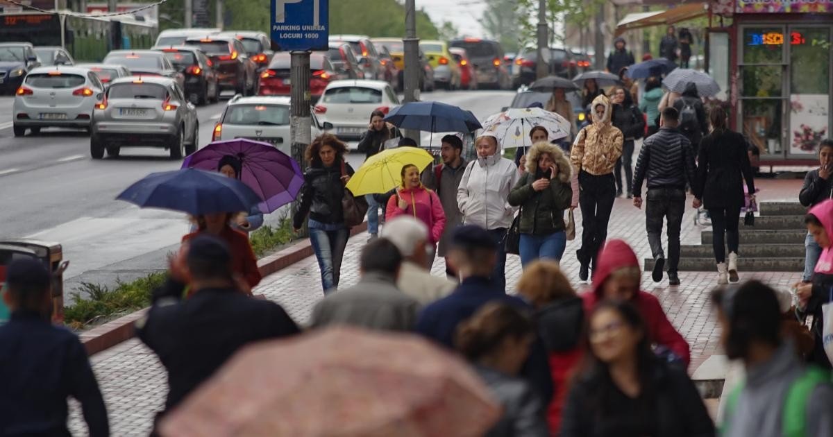 Прохожие с зонтами на городской улице во время сильного дождя, вызванного циклоном «Дебора»