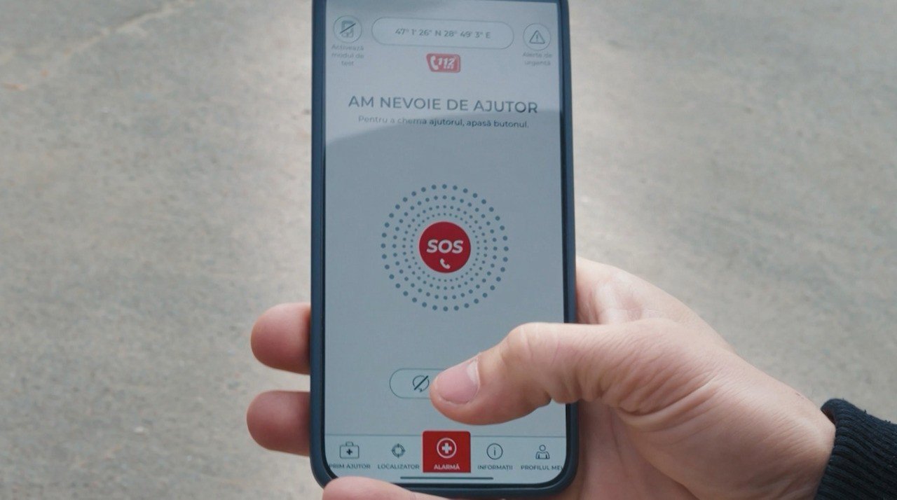 Пользователь держит смартфон с открытым приложением 112MD на улице, на экране — кнопка SOS
