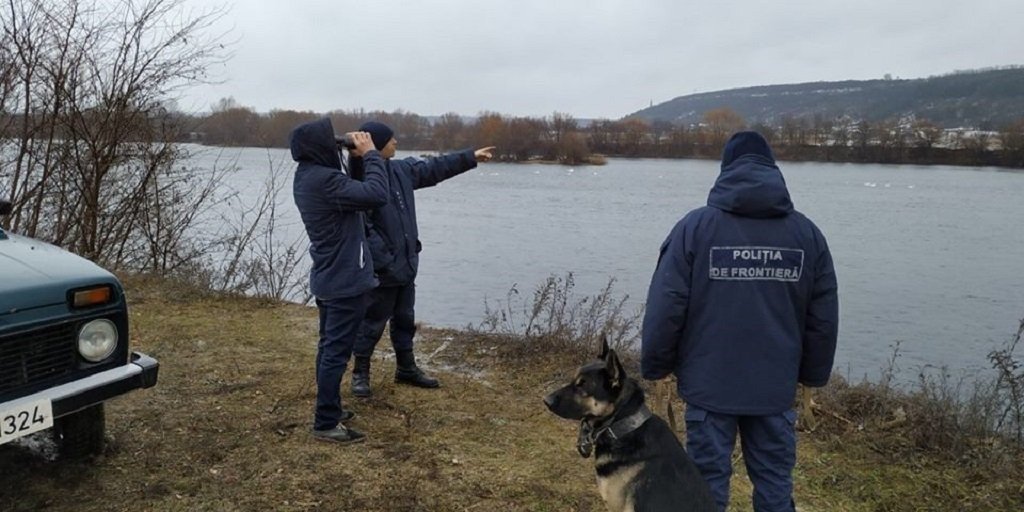 Сотрудники пограничной полиции Молдовы с биноклем наблюдают за границей у реки