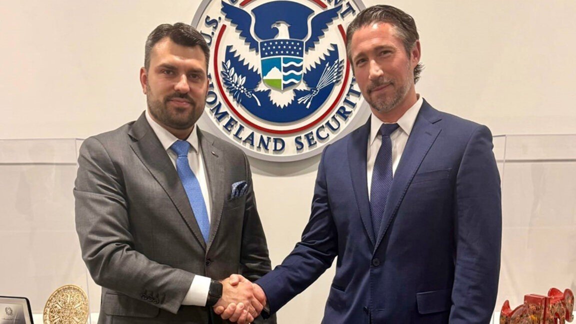 Министр внутренних дел Болгарии пожимает руку представителю Министерства внутренней безопасности США на фоне эмблемы ведомства