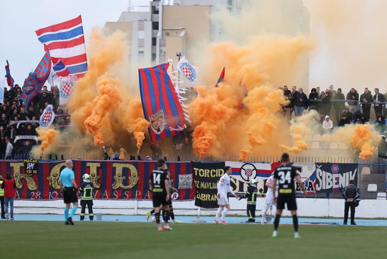 Болельщики «Хайдука» из группировки Torcida зажигают оранжевые дымовые шашки и размахивают флагами на трибуне стадиона