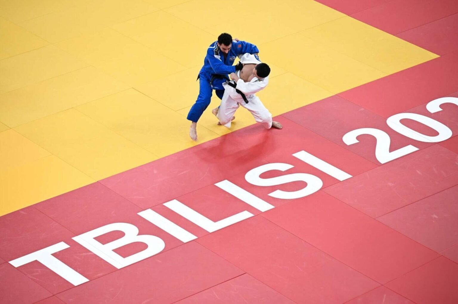 Вид сверху на поединок двух дзюдоистов на татами с надписью «TBILISI» во время турнира Большого шлема в Тбилиси 2026