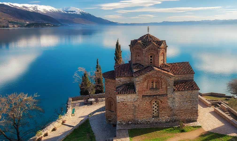 Церковь Святого Иоанна Канео с видом на Охридское озеро и заснеженные горы на заднем плане. Фото: Henley & Partners
