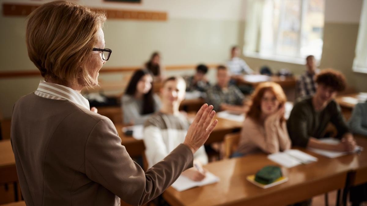 Учительница обращается к ученикам в школьном классе во время занятия