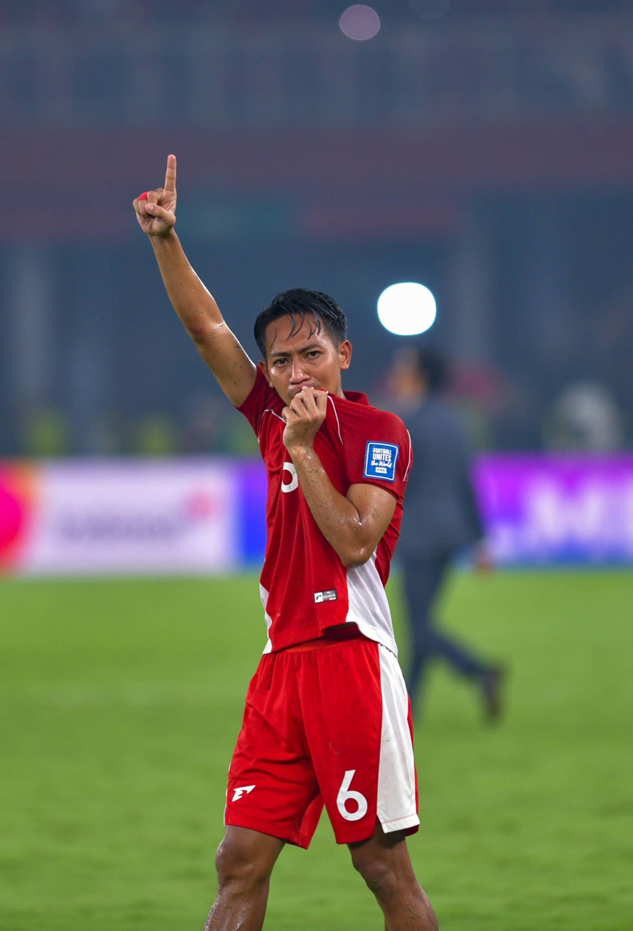 Игрок сборной Индонезии (№6) празднует победу на поле после матча FIFA Series 2026, поднимая палец вверх