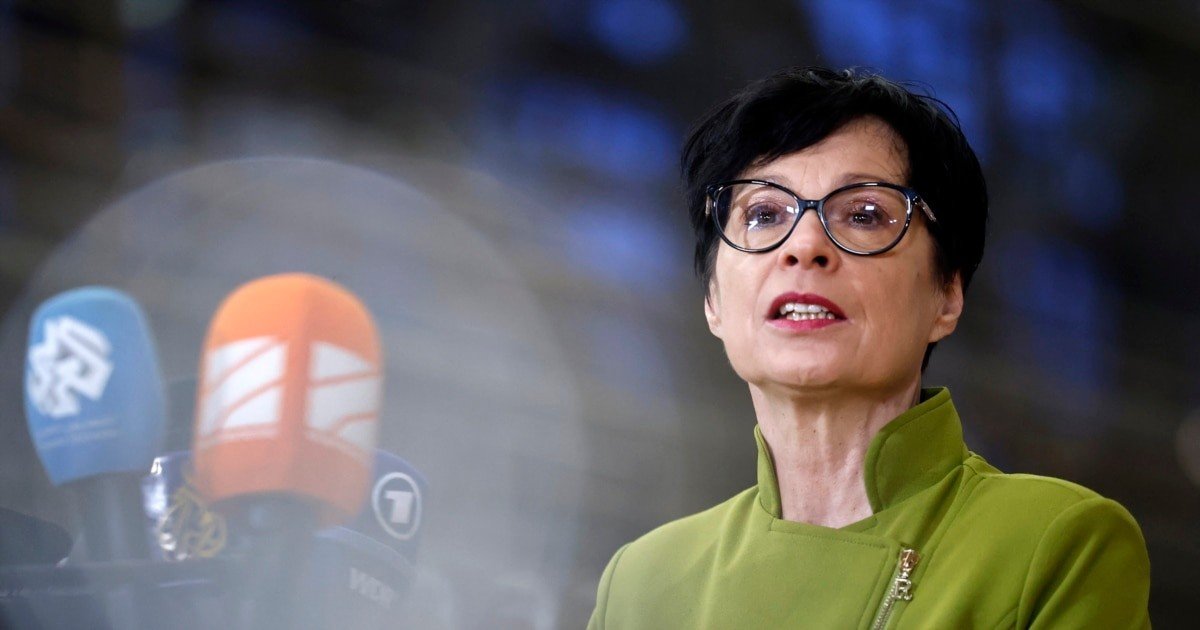 Марта Кос на пресс-конференции в зелёном пиджаке перед журналистскими микрофонами